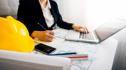 Two colleagues discussing data working and tablet, laptop with architectural project at construction site at desk in office