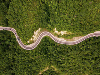 Mountain winding zig zag road. Top aerial view: cars driving on road from above.