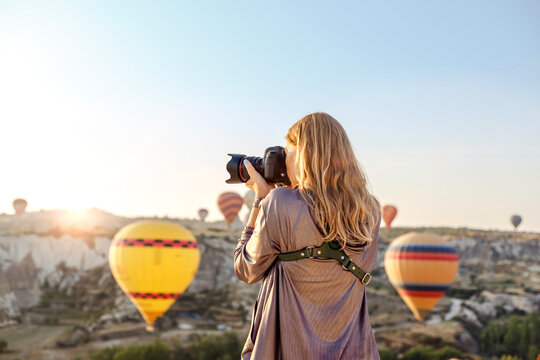 Woman photographer takes pictures of flying hot air balloon