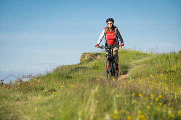 pretty senior woman riding her electric mountain bike on the mountains above Oberstaufen, Allgau Alps, Bavaria Germany 
