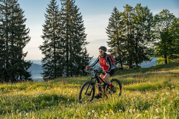 Naklejka premium pretty senior woman riding her electric mountain bike on the mountains above Oberstaufen, Allgau Alps, Bavaria Germany 