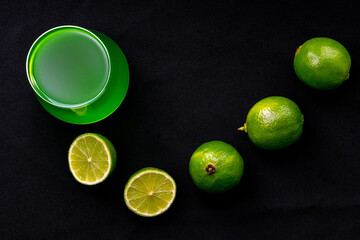 Glass of mojito or natural lemonade with lime slices, on black background.
