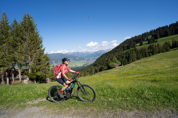 Fototapeta na wymiar pretty senior woman riding her electric mountain bike on the mountains above the Iller valley between Sonthofen and Oberstdorf, Allgau Alps, Bavaria Germany 