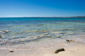 Mare trasparente con sabbia bianca, scogli e cielo sereno