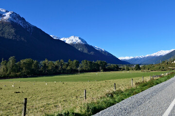 Mountain road in the Southern Alps in New Zealand on a winter day with a clear blue sky and snowy peaks