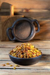 Black Raisins in the bowl on wooden rustic background 