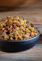 Golden Raisins in the bowl on wooden rustic background 