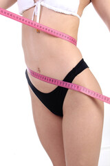 Weight loss background. Proud beautiful fitness woman measuring her body with pants and measuring tape. 