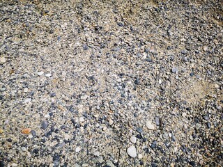 background of sand and small stones of gray color by the Ligurian sea