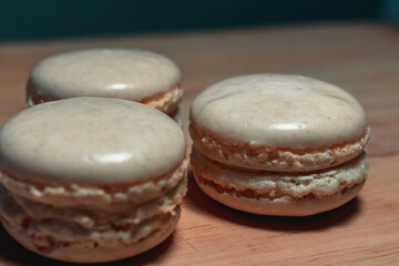 Three white macarons on wood with bleu background