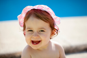 Bebé de quince meses sonriendo junto a la piscina