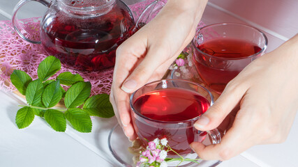 A woman holds a mug of tea. Red tea, hibiscus, karkade, Rooibos. Ceremony, afternoon tea, Breakfast. Tea time, carcade. Oriental, cozy, tradition, japanese, leafy, hygge, autumn, 5 o'clock, cup