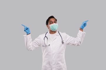 Indian Man Doctor Pointing to Sides both Hands Wearing Medical Mask and Gloves. Isolated