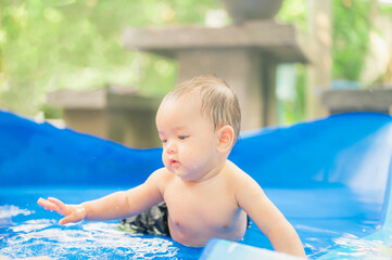 Fototapeta na wymiar Asian baby boy playing in swimming pool, during quarantine,Fun holiday concept.