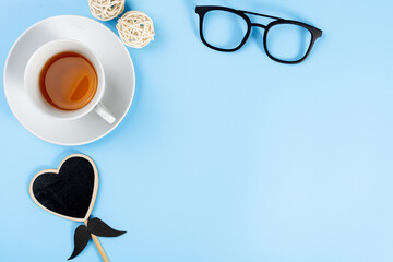 Happy Father Day background concept with glasses, cup of tea and black heart shape on blue background with copy space for text.