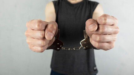 man's hands in handcuffs against a concrete wall