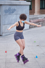 Latin girl skating on inline skates protecting herself with a face mask