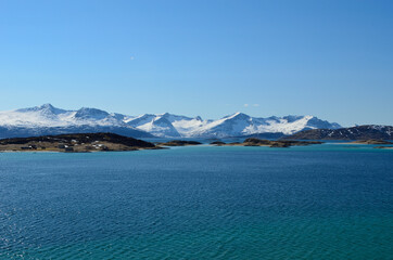 small settlement on sea islands with snowy mountains and sunshine