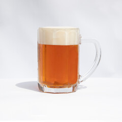 Beer mug of light beer with white foam in a mug on white background