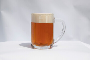 Poured semi dark beer with foam in a glass on white background.