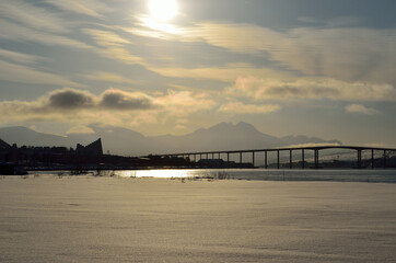 warming sunrise over snowy field and mountain with cathedral and tromsoe city island and mainland in the background