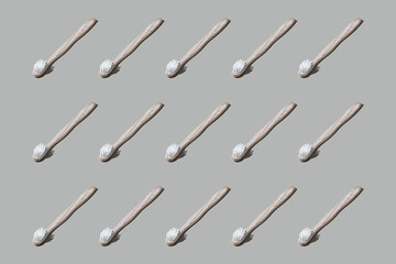 Colourful pattern of toothbrushes on grey background. View from top.