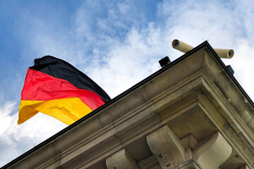 CCTV cameras on the corner of a building with the German flag flying in the background.