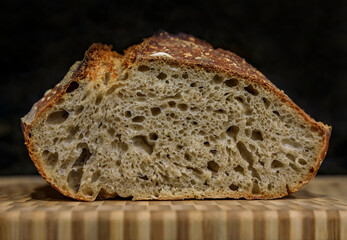 Sliced loaf of artisanal whole wheat and dark rye rustic sourdough bread on a cutting board, baked at home, photo series