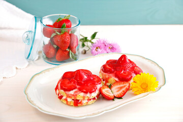 fresh strawberries in green glass, jar with tablecloth and flower background. Sweet strawberry natural fruits in Glass can. mini Strawberry and Yogurt cream sponge cake on plate. 