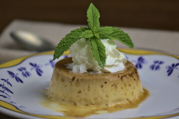 Flan de queso, postre tradicional español,  con nata montada y hojas de menta 