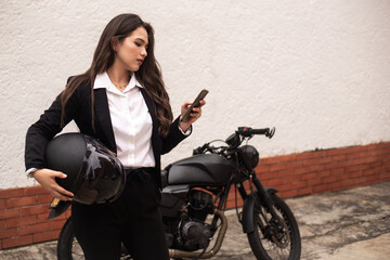 Fototapeta na wymiar woman using cell phone before getting on her motorcycle