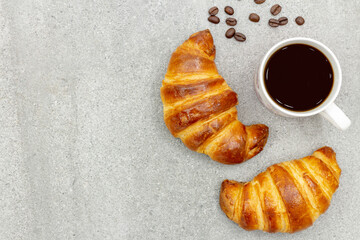 Tasty fresh croissants and a coffee mug on the table