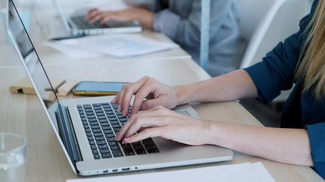 Video of close-up of two business women work with laptops on the partitioned desk in the coworking space. Concept of social distancing.