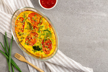 Tasty vegetable casserole with broccoli in a glass baking dish on a gray background