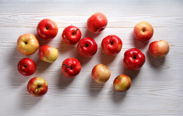 Fototapeta na wymiar red apples scattered on a white wooden table, flat lay
