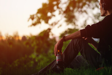 A man sits on the grass in the Park, listening to music, drinking beer. Relax and enjoy your life