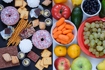 Healthy and unhealthy food concept, fruits and vegetables vs donuts, sweets and chocolate with woman's hand. Top view