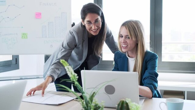 Video of two business women working together with laptop in the office.