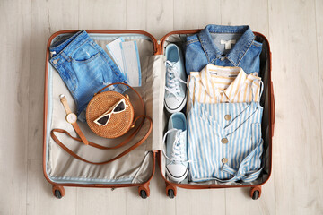 Open packed suitcase on wooden background