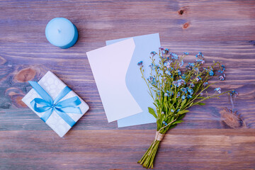 Mockup wedding invitation and envelope with blue flowers on a wooden table