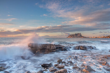 Paisaje de costa de la cala baladrar, en el mar mediterráneo, atardecer dentro del agua, y el peñón de Ifach de Calpe en el fondo del encuadre.