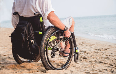 Disabled man in a wheelchair on the beach.