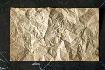 rumpled sheet of old paper on a black background