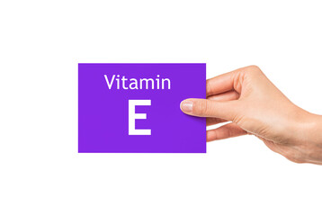 Vitamin E. Female hand shows a card with the inscription Vitamin E.