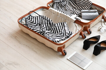 Fototapeta na wymiar Open packed suitcase and accessories on wooden background