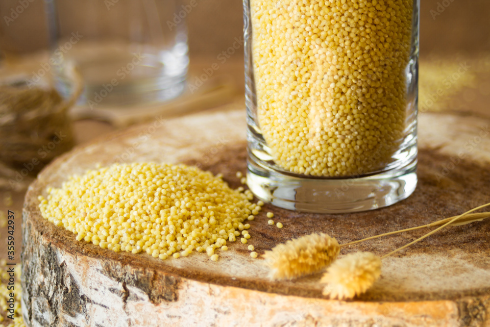 Wall mural millet in a glass jar on a wooden stand, next is an ear of wheat