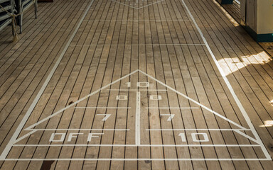 A shuffle-board playing surface on the promenade deck of a cruise ship featuring its distinctive triangle and numbers.