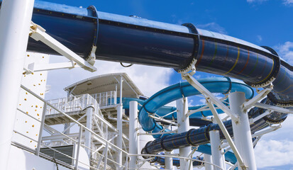 Two intertwining blue water slides on the uppermost deck of a cruise ship.