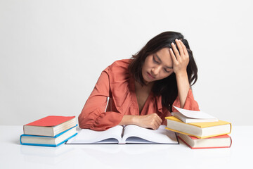 Exhausted Young Asian woman read a book with books on table .