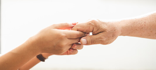 Woman hand holding old senior elder hand with love and care